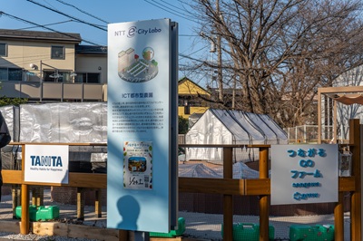 Escena de la visita dentro de NTT e-City Labo. En la parte derecha de la pantalla se lee "Granja", y se opera un huerto para hogares como una forma de agricultura urbana.