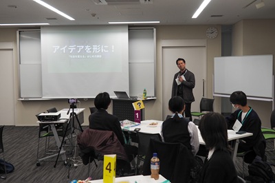 Escena de la conferencia. Kazunari Tanimura, líder del equipo Green Bird Koenji, está hablando a los participantes.